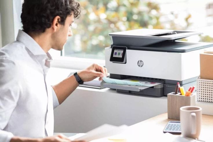 A man using an HP 123 Setup in a bright office setting, printing colorful documents.